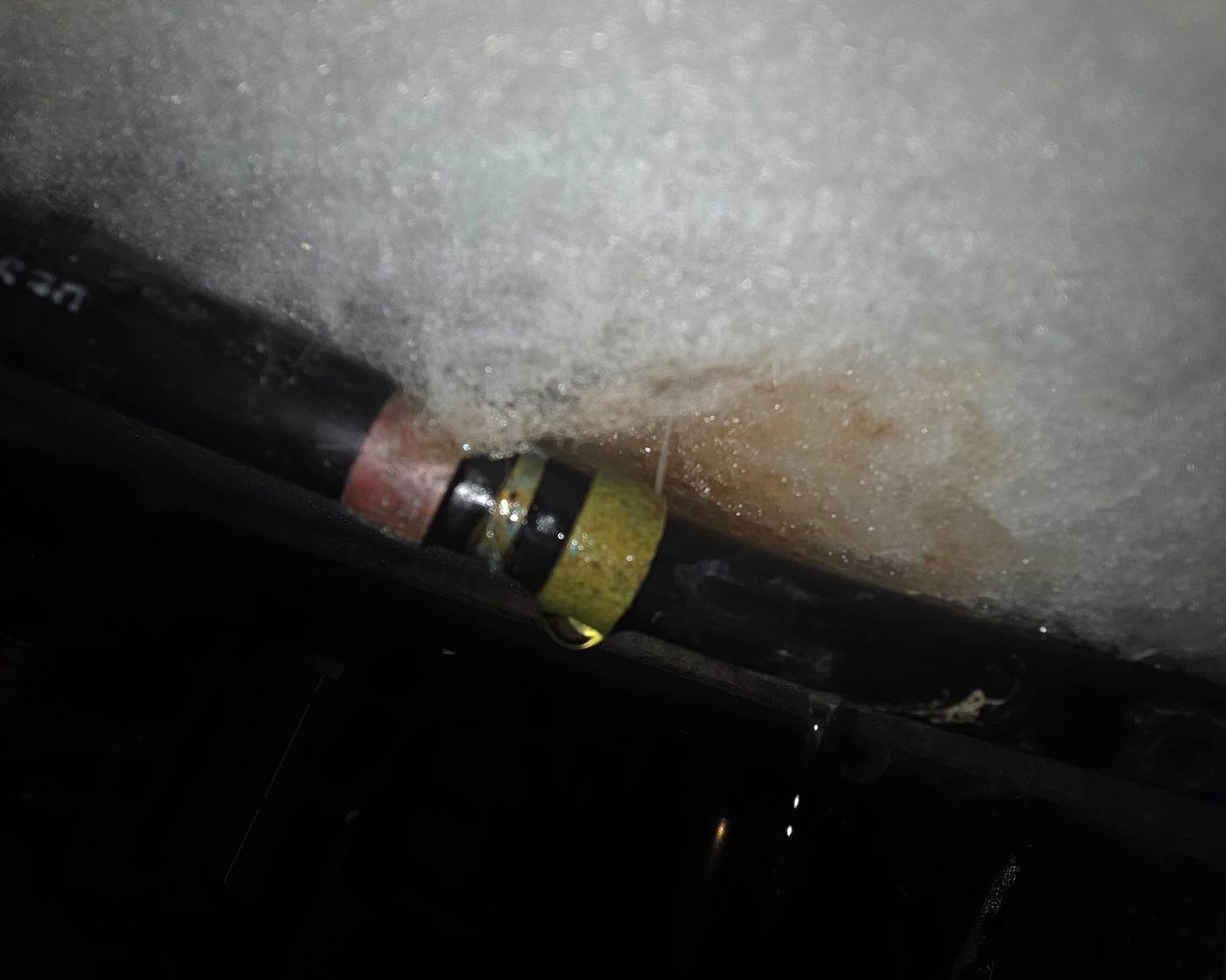 Black Dux Quest pipe under a floor in West Harbour, leaking at a joint fitting, with a brown water stain on the insulation above