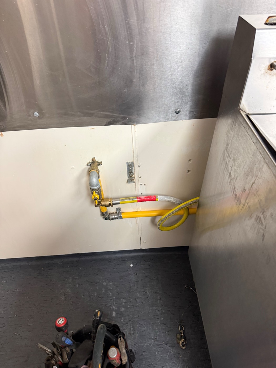 A commercial gas regulator and hose connection in a kitchen