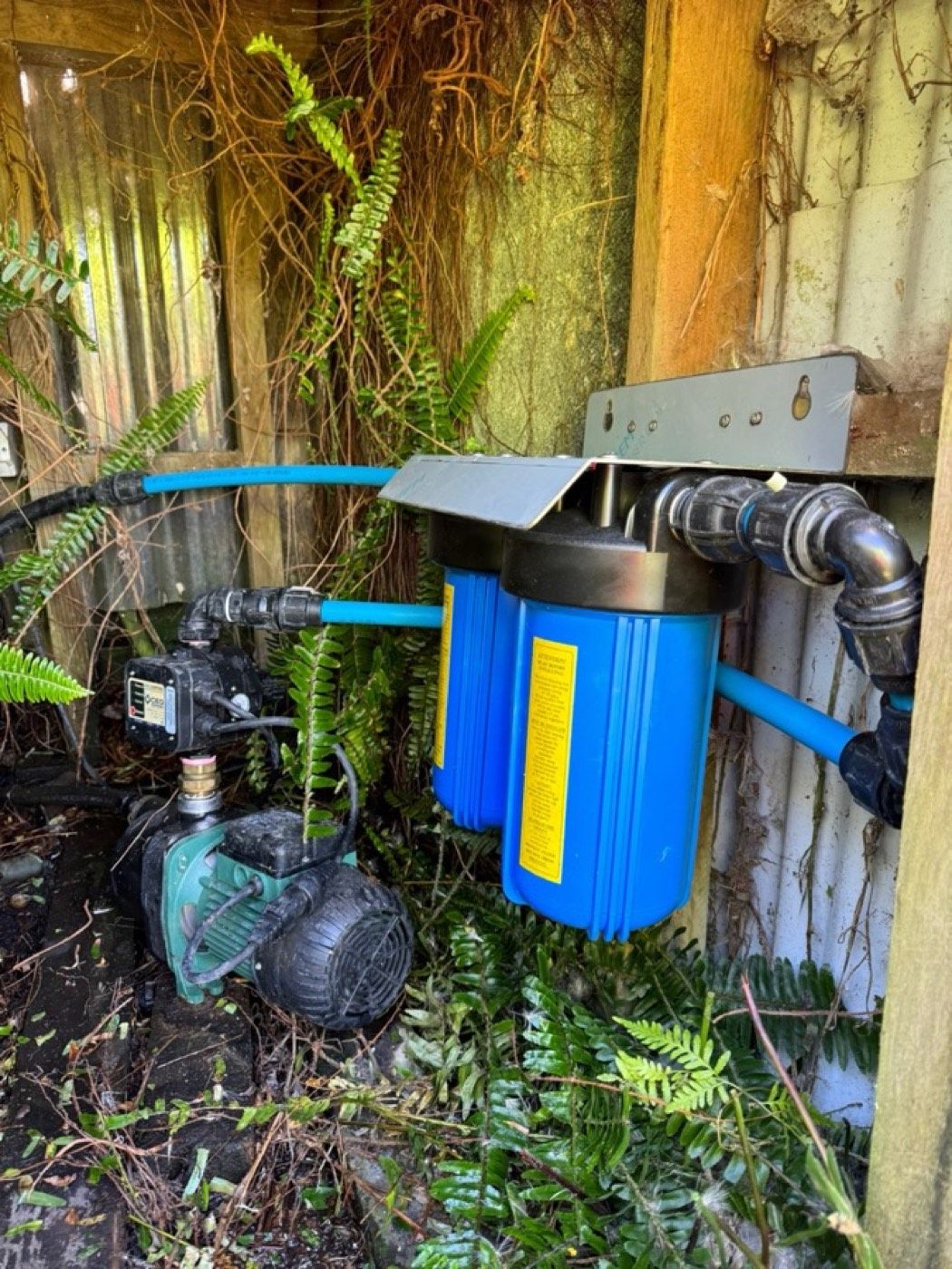 A twin whole-house water filter mounted beside the pump for a rainwater tank supply