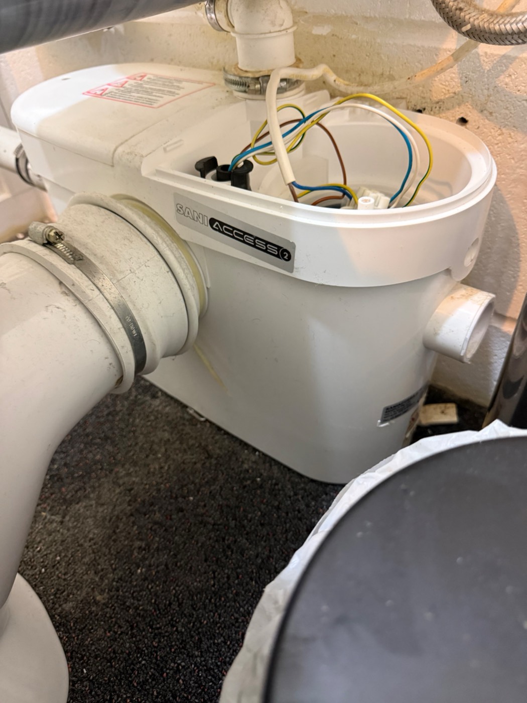 A Saniflo unit opened up for inspection, showing the internal wiring and chamber