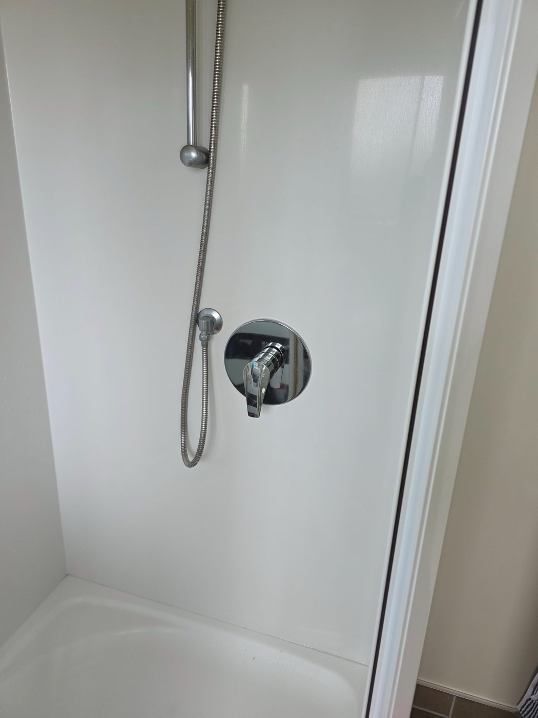 A replacement shower mixer fitted with a large jumbo faceplate covering the opening, on an unmarked shower liner