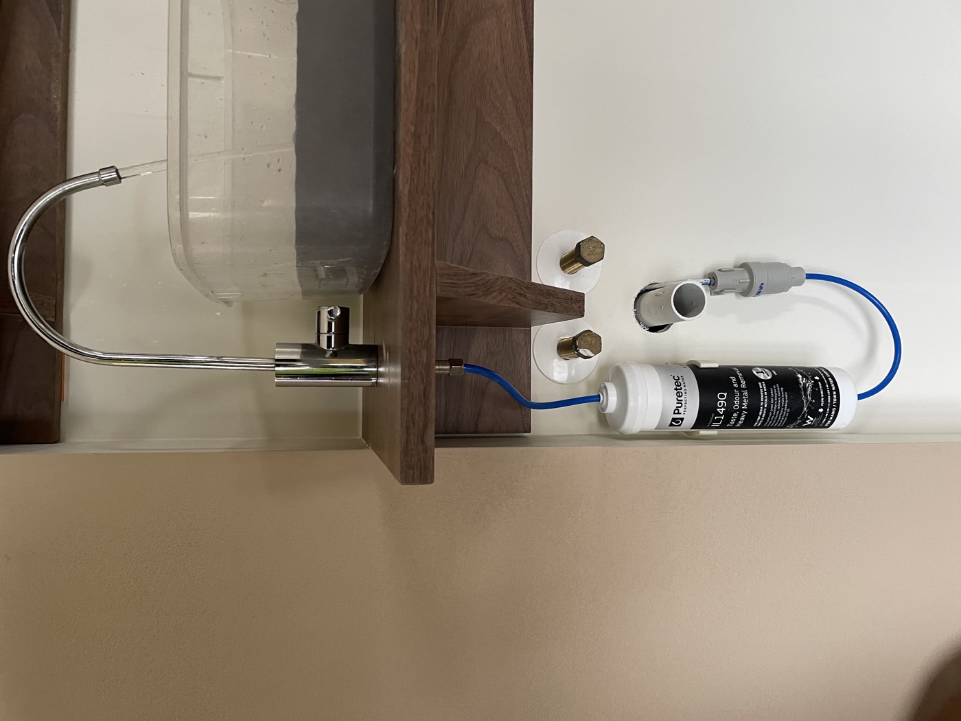 A dedicated filtered water tap running above the bench, with the Puretec cartridge and its blue feed line in the cabinet below