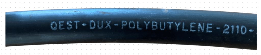 Grey Dux Qest polybutylene pipe with the name printed along it