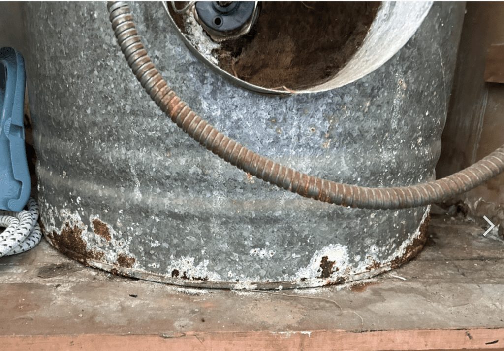 A rusted cylinder base sitting on a damp timber floor